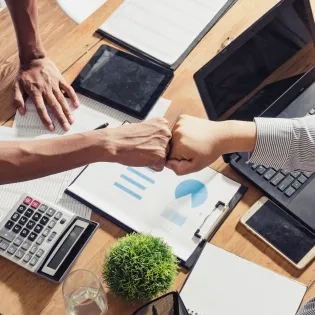 os profesionales celebran con un choque de puños el éxito en la eficiencia empresarial mediante el análisis de datos, enfoque de la Ingeniería Industrial Ibero.